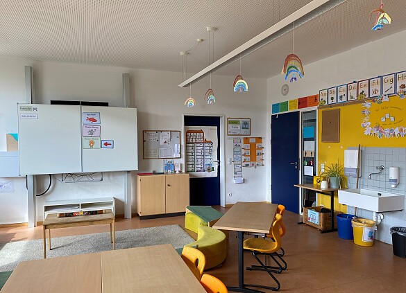 Klassenraum mit Tafel, Sitzkreis, Tischen und Waschbecken