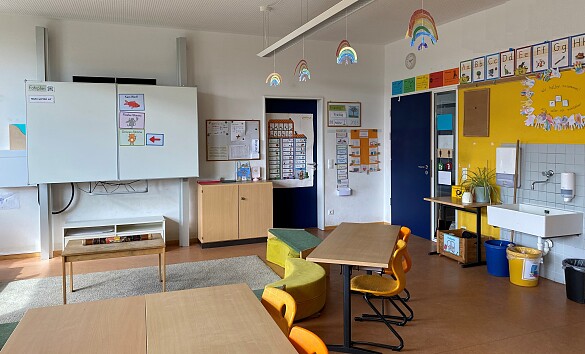 Klassenraum mit Tafel, Sitzkreis, Tischen und Waschbecken