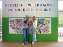 Herzlich Willkommen in unserer Schule Schild und zwei Kolleginnen mit Einstern und Lola